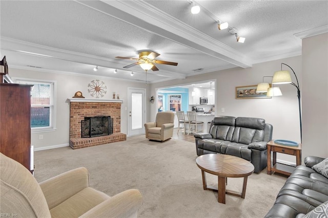 carpeted living room featuring beam ceiling, a fireplace, ornamental molding, track lighting, and a textured ceiling