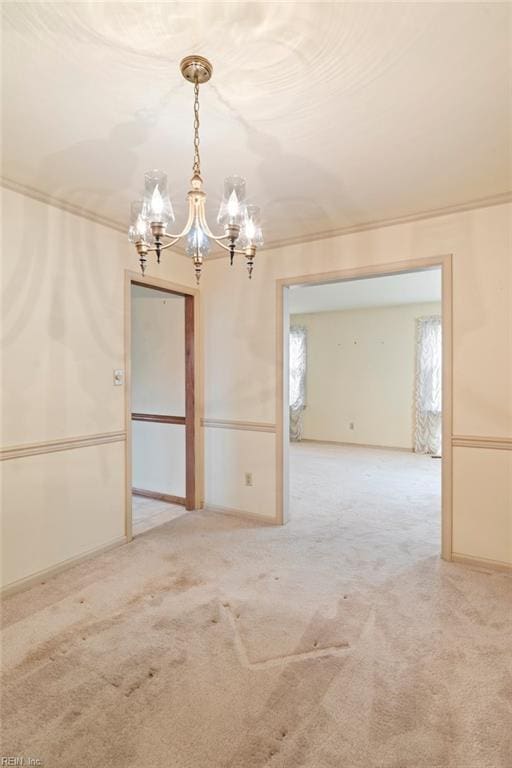 carpeted spare room with an inviting chandelier and ornamental molding