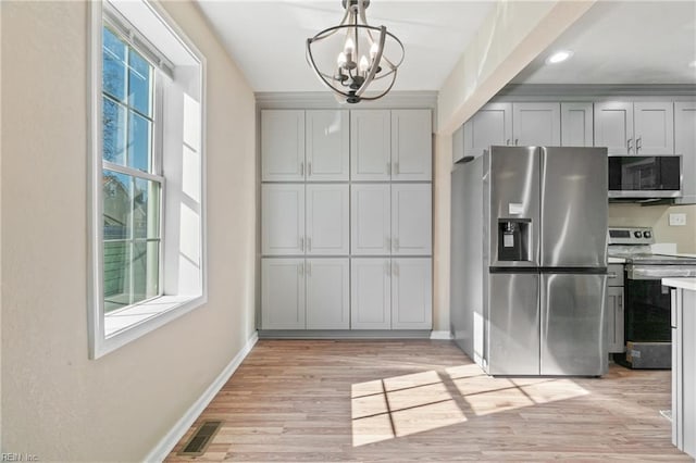 kitchen featuring decorative light fixtures, light wood-type flooring, appliances with stainless steel finishes, gray cabinets, and a notable chandelier