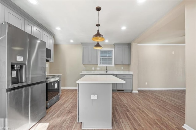 kitchen featuring gray cabinets, appliances with stainless steel finishes, sink, hanging light fixtures, and light hardwood / wood-style flooring