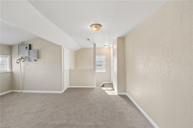 carpeted spare room with vaulted ceiling and water heater