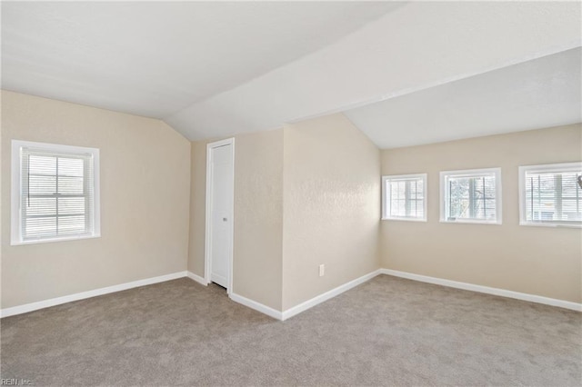 bonus room featuring lofted ceiling, plenty of natural light, and light colored carpet