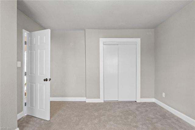 unfurnished bedroom featuring light carpet and a closet