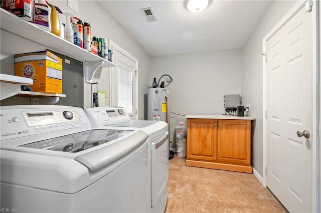 clothes washing area with water heater, washer and dryer, and cabinets