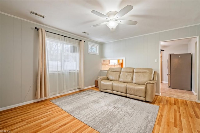 living room with crown molding, ceiling fan, and light wood-type flooring