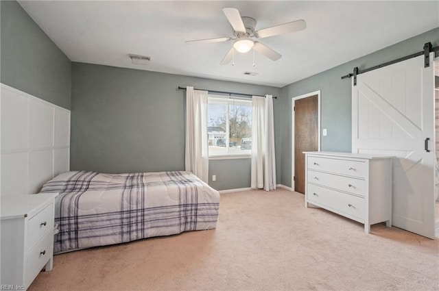 carpeted bedroom featuring ceiling fan and a barn door