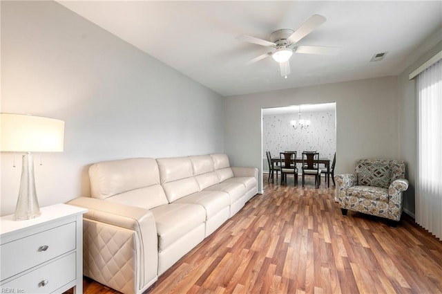 living room with hardwood / wood-style floors and ceiling fan with notable chandelier