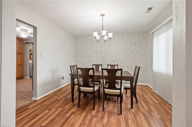 dining space with hardwood / wood-style flooring and a notable chandelier