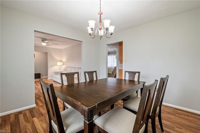 dining space featuring dark wood-type flooring and an inviting chandelier