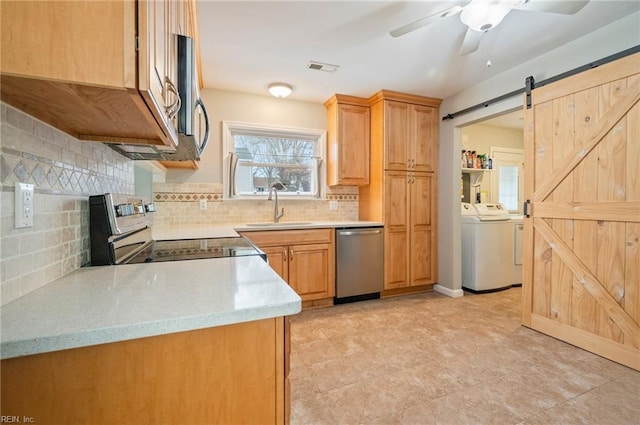 kitchen featuring tasteful backsplash, sink, independent washer and dryer, stainless steel appliances, and a barn door