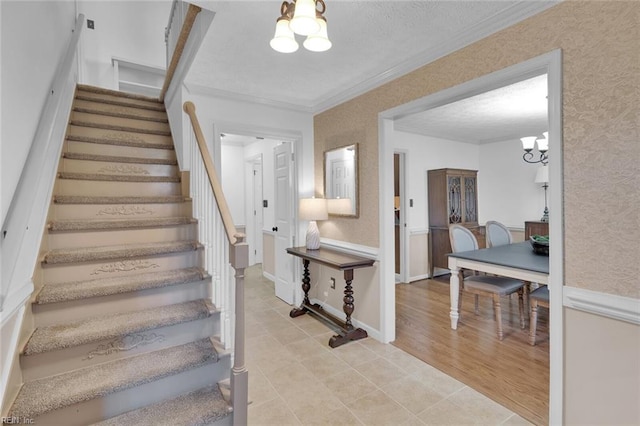 staircase featuring ornamental molding, a chandelier, wood-type flooring, and a textured ceiling