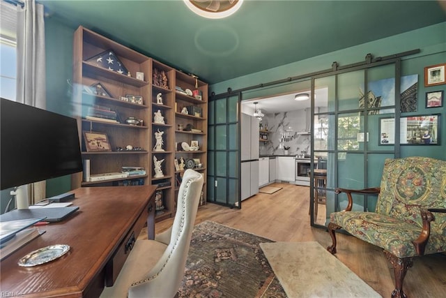 office space featuring a barn door and light wood-type flooring