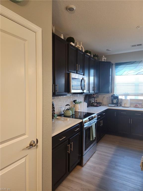 kitchen featuring appliances with stainless steel finishes, light hardwood / wood-style floors, and decorative backsplash