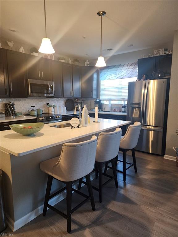 kitchen featuring sink, decorative light fixtures, a kitchen breakfast bar, stainless steel appliances, and a kitchen island with sink