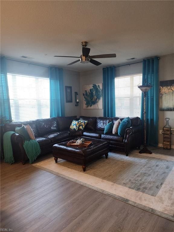 living room with ceiling fan, wood-type flooring, and a healthy amount of sunlight