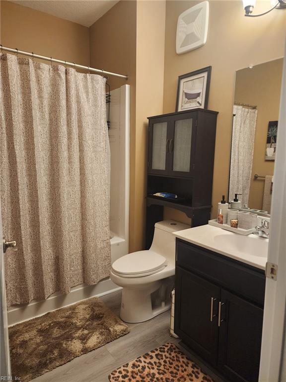 full bathroom featuring vanity, hardwood / wood-style floors, toilet, and shower / bath combo with shower curtain