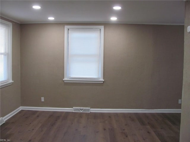 spare room with ornamental molding and dark wood-type flooring