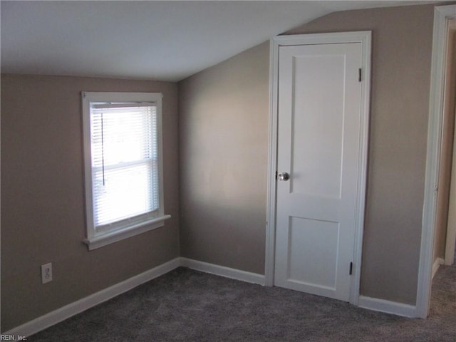 unfurnished bedroom featuring vaulted ceiling and dark colored carpet