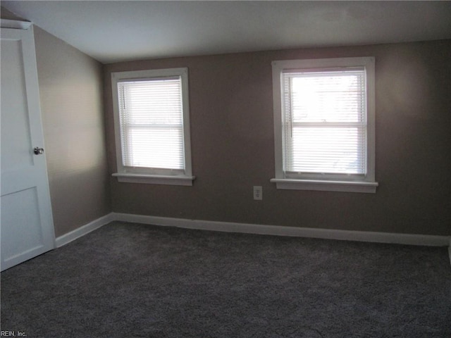 spare room with dark carpet