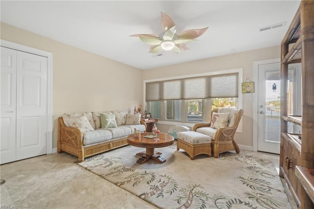 living area featuring baseboards, visible vents, and a ceiling fan