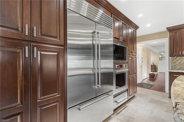 kitchen featuring built in appliances, light stone counters, recessed lighting, decorative backsplash, and a warming drawer