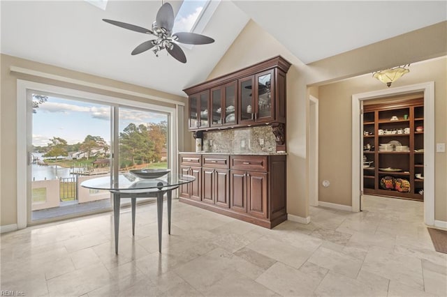 bar with lofted ceiling, ceiling fan, baseboards, and decorative backsplash