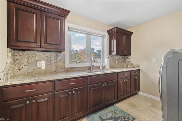 kitchen with tasteful backsplash, washer / dryer, sink, and light stone counters