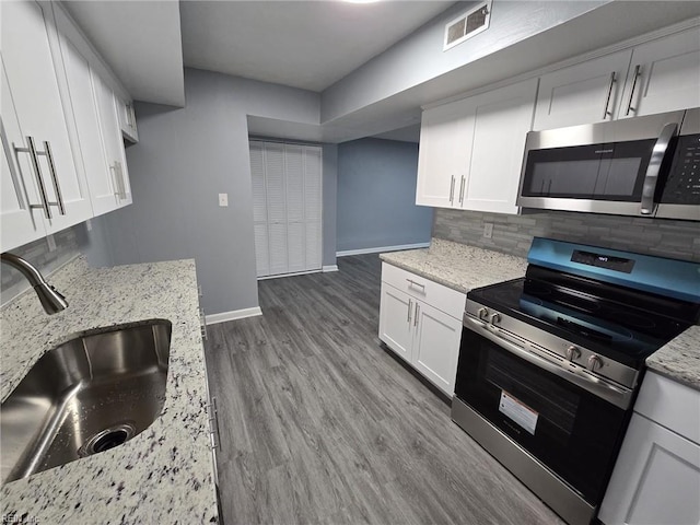 kitchen featuring sink, appliances with stainless steel finishes, white cabinetry, backsplash, and light stone counters