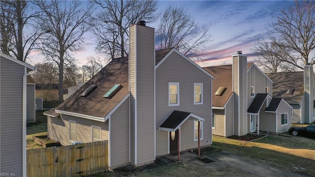 back house at dusk featuring a lawn