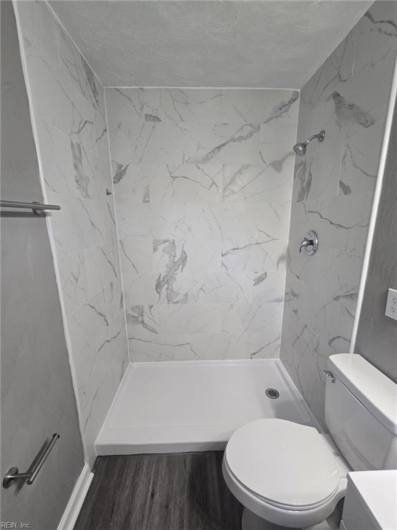 bathroom featuring a tile shower, vanity, hardwood / wood-style flooring, and toilet