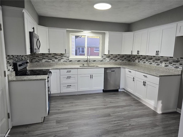 kitchen featuring sink, white cabinetry, light stone counters, light wood-type flooring, and appliances with stainless steel finishes