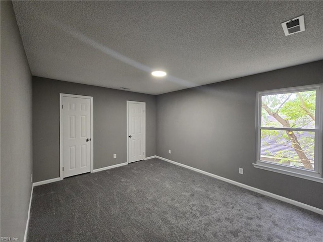 unfurnished room featuring dark carpet and a textured ceiling