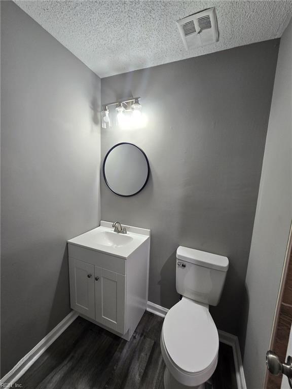 bathroom with vanity, hardwood / wood-style floors, a textured ceiling, and toilet