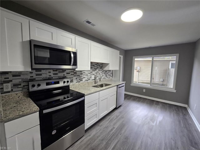 kitchen with sink, white cabinetry, appliances with stainless steel finishes, light stone countertops, and decorative backsplash