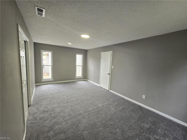 carpeted empty room featuring a textured ceiling