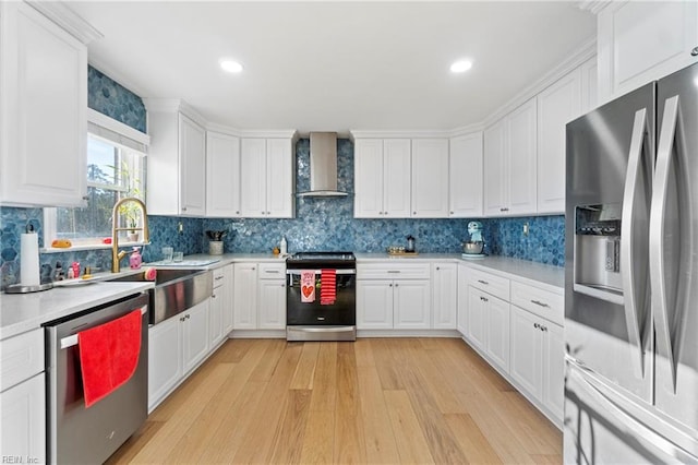 kitchen with white cabinetry, wall chimney range hood, stainless steel appliances, and sink