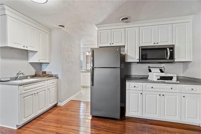 kitchen with sink, stainless steel appliances, hardwood / wood-style floors, and white cabinets