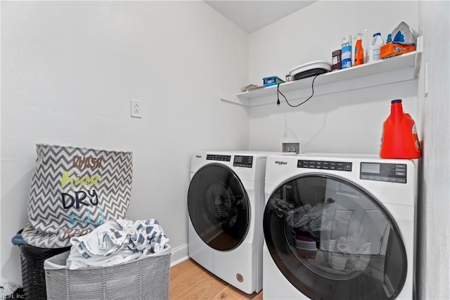 clothes washing area with washer and dryer and light hardwood / wood-style floors