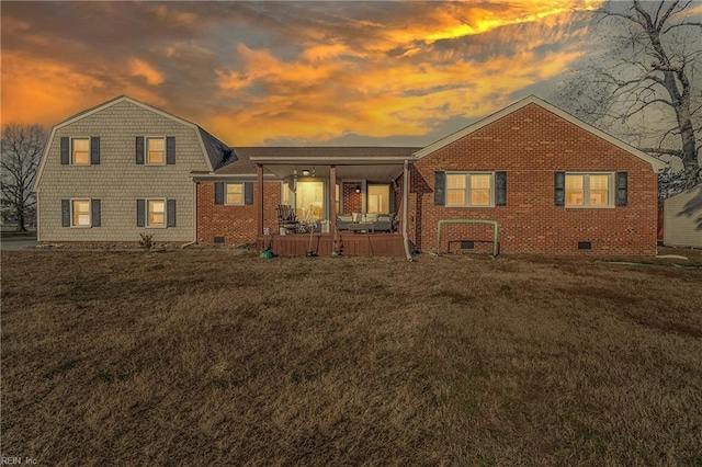 back house at dusk with covered porch and a lawn