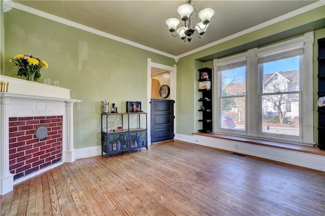 unfurnished living room featuring a fireplace, crown molding, light hardwood / wood-style flooring, and a chandelier