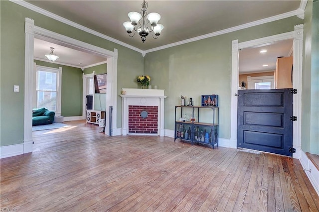 living room with crown molding, wood-type flooring, a fireplace, and an inviting chandelier