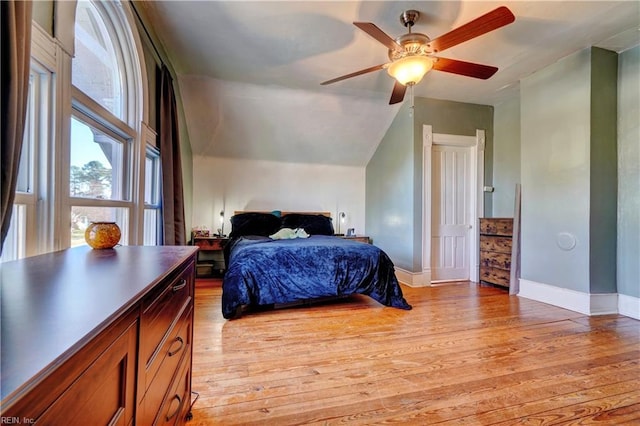 bedroom with ceiling fan, lofted ceiling, and light wood-type flooring