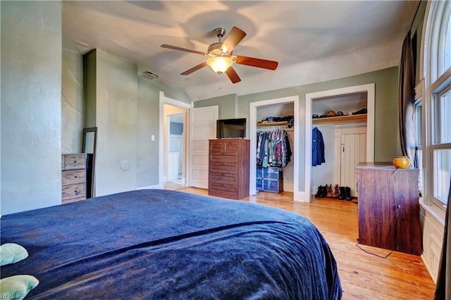 bedroom with multiple closets, ceiling fan, and light hardwood / wood-style floors