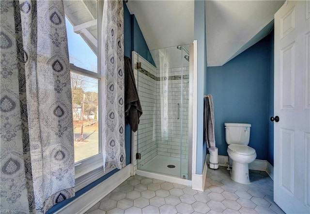 bathroom with a shower with door, a healthy amount of sunlight, tile patterned flooring, and toilet