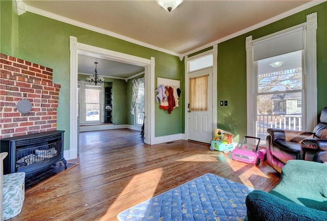 living room featuring crown molding, an inviting chandelier, a fireplace, and hardwood / wood-style floors