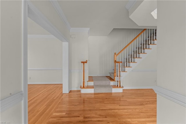 staircase with hardwood / wood-style floors, a skylight, and ornamental molding