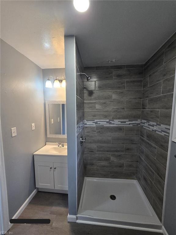 bathroom with a tile shower and vanity