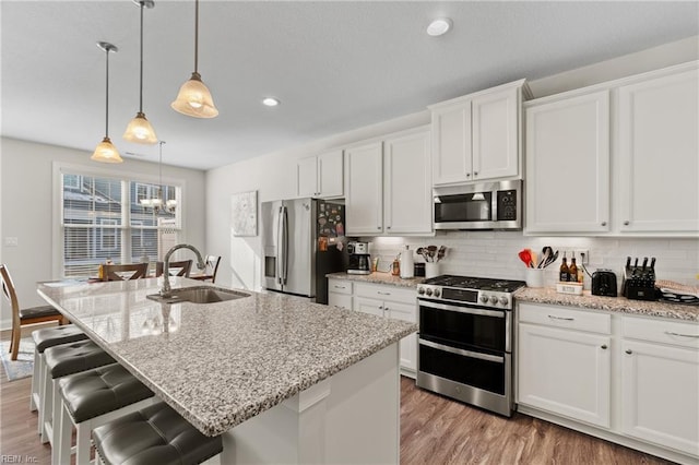 kitchen with a kitchen island with sink, sink, white cabinetry, and stainless steel appliances