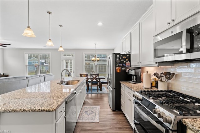 kitchen featuring stainless steel appliances, a kitchen island with sink, pendant lighting, and white cabinets