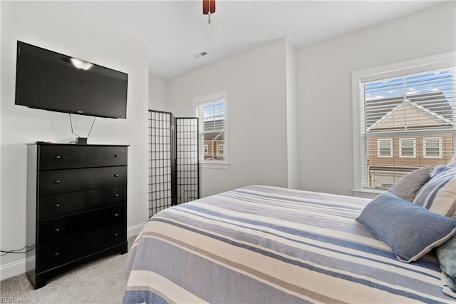 carpeted bedroom featuring multiple windows and ceiling fan